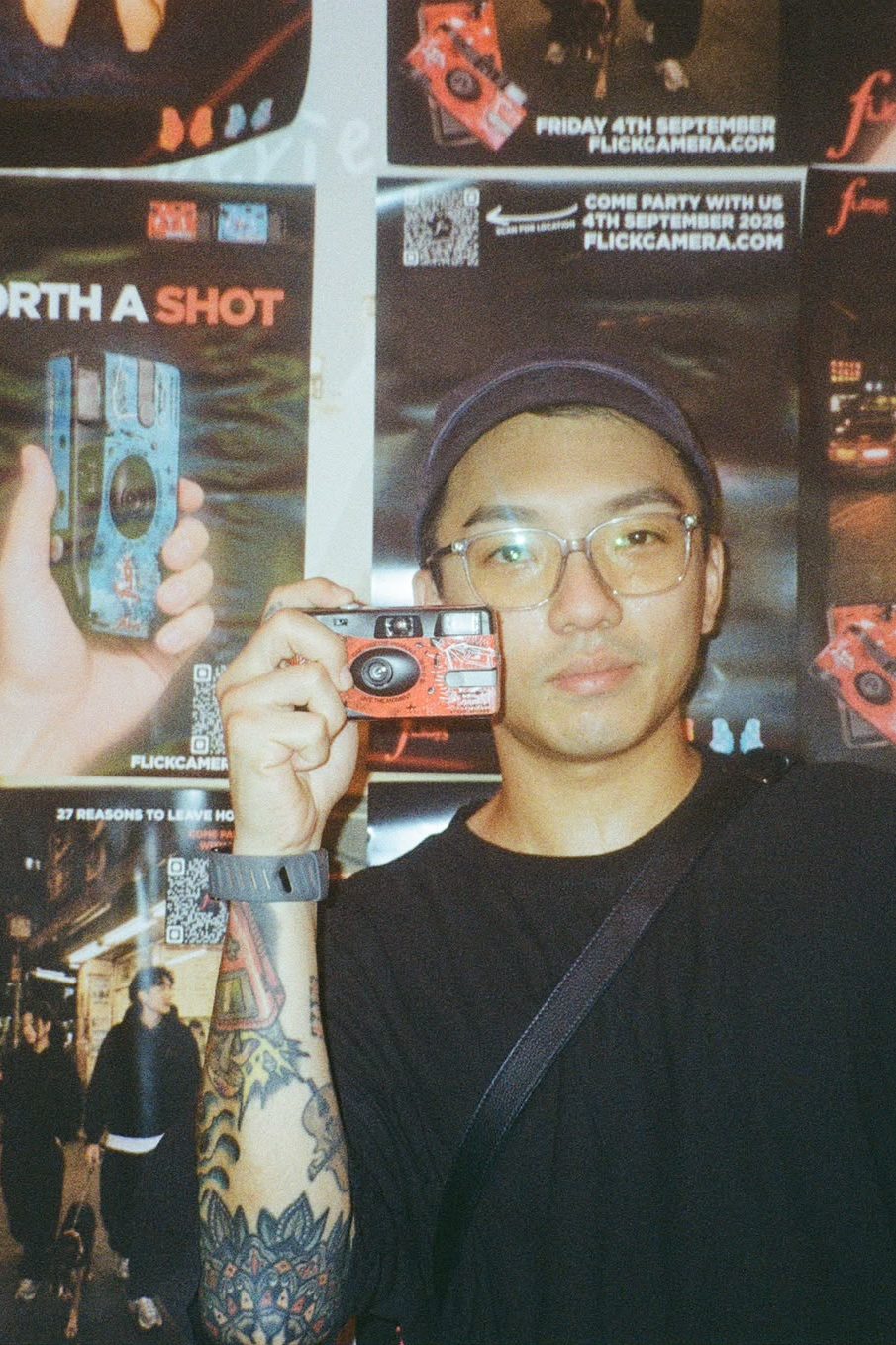 Guest raising a Flick camera to his eye in front of the launch party poster wall